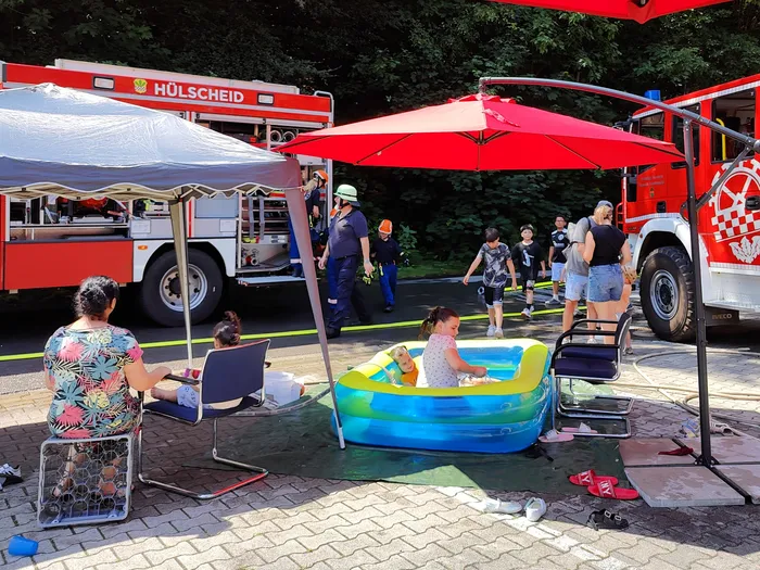Open day at the Schalksmühle fire station with a fire truck in the background and people gathered around a paddling pool.