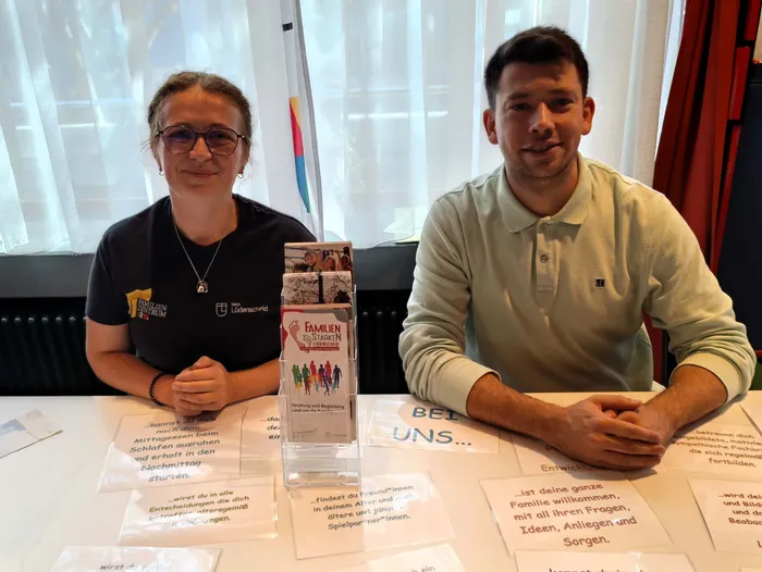 Eine Frau und ein Mann sitzen an einem Tisch mit Informationsmaterialien des Familienzentrums Lüdenscheid.