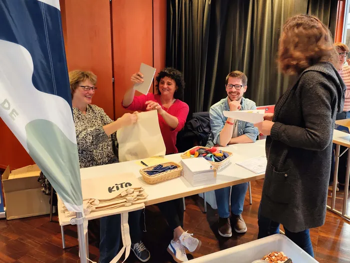 Personen verteilen Stofftaschen und kleine Geschenke an einem Tisch bei einem Neugeborenen-Empfang.