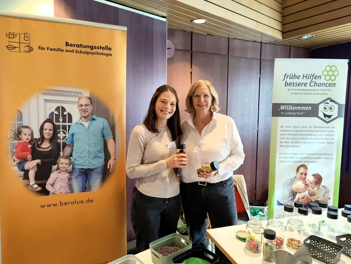 Zwei Frauen stehen an einem Infostand mit Bannern der Beratungsstelle für Familie und Schulpsychologie und des Programms „frühe Hilfen“.