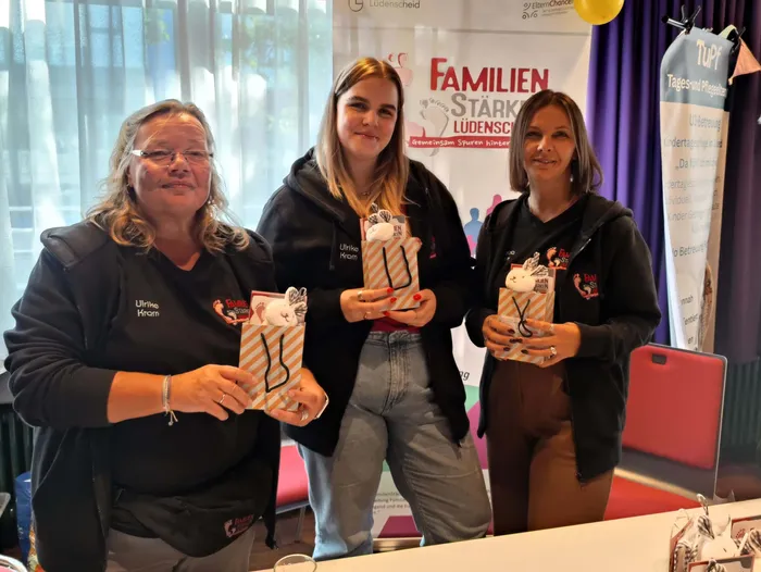 Drei Frauen halten kleine, verzierte Geschenktüten mit Hasenmotiv bei einem Neugeborenen-Empfang in Lüdenscheid.