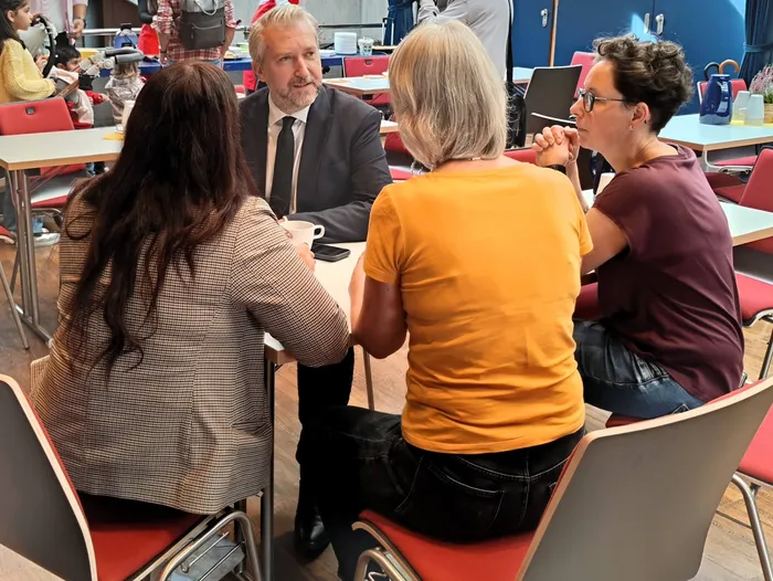Ein Mann im Anzug unterhält sich mit drei Frauen an einem Tisch während des Neugeborenen-Empfangs im Kulturhaus Lüdenscheid.