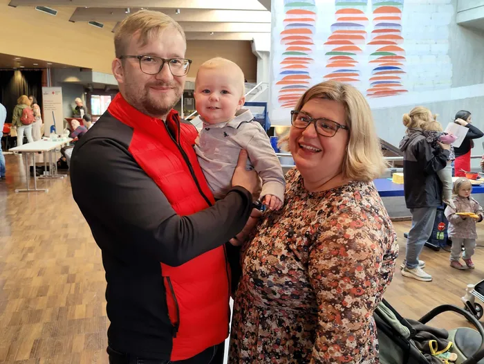 Ein Mann und eine Frau halten ein lächelndes Baby im Arm.