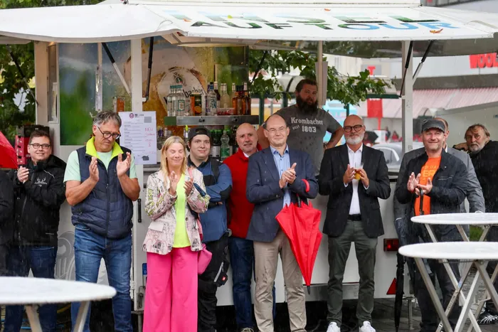 Eine Gruppe von Menschen applaudiert vor einem Verkaufsstand beim Brückenfest 2026.