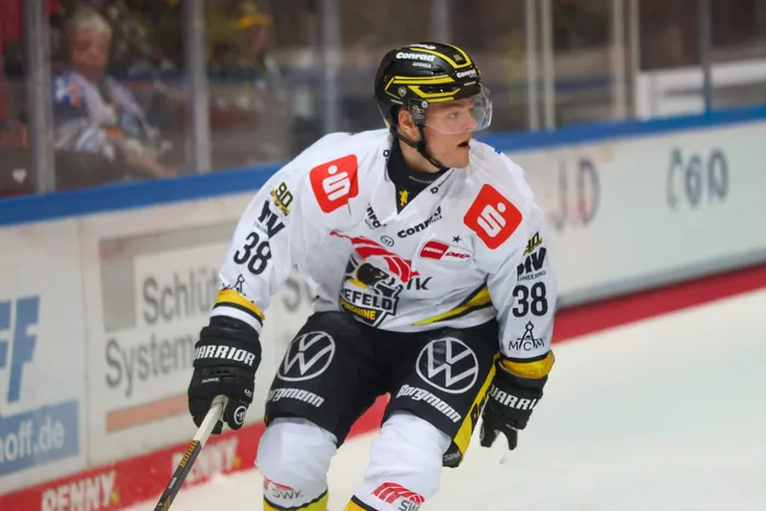 Eishockeyspieler der Iserlohn Roosters mit der Nummer 38 in weißem Trikot auf dem Eis.