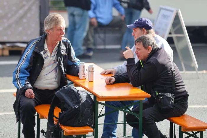 Drei Männer unterhalten sich an einem orangefarbenen Biertisch beim Brückenfest.