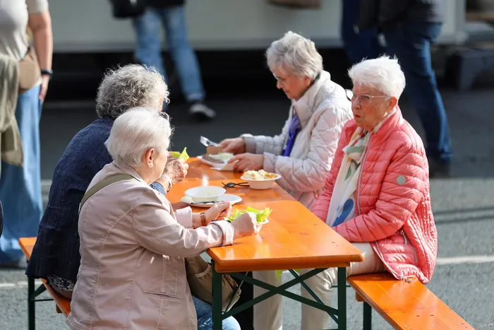 Vier ältere Frauen sitzen an einem Holztisch und essen gemeinsam beim Brückenfest 2026.