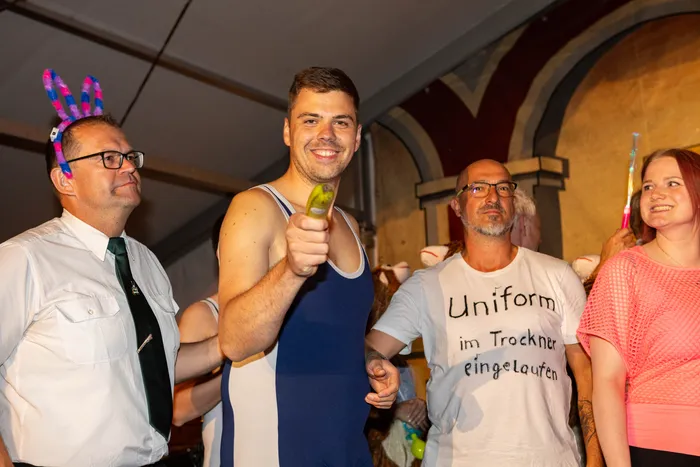 Vier Personen bei einem bunten Dorfabend, darunter ein Mann mit Hasenohren und ein Mann in einem T-Shirt mit der Aufschrift „Uniform im Trockner eingelaufen“.