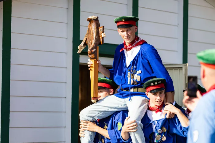 Der neue Jungschützenprinz Luca Benninghaus wird auf den Schultern von anderen Jungschützen durch Meinerzhagen getragen. Er trägt eine blaue Uniform mit vielen Orden und eine grüne Schützenmütze. In der Hand hält er einen Vogelstab mit dem abgeschossenen Vogel.