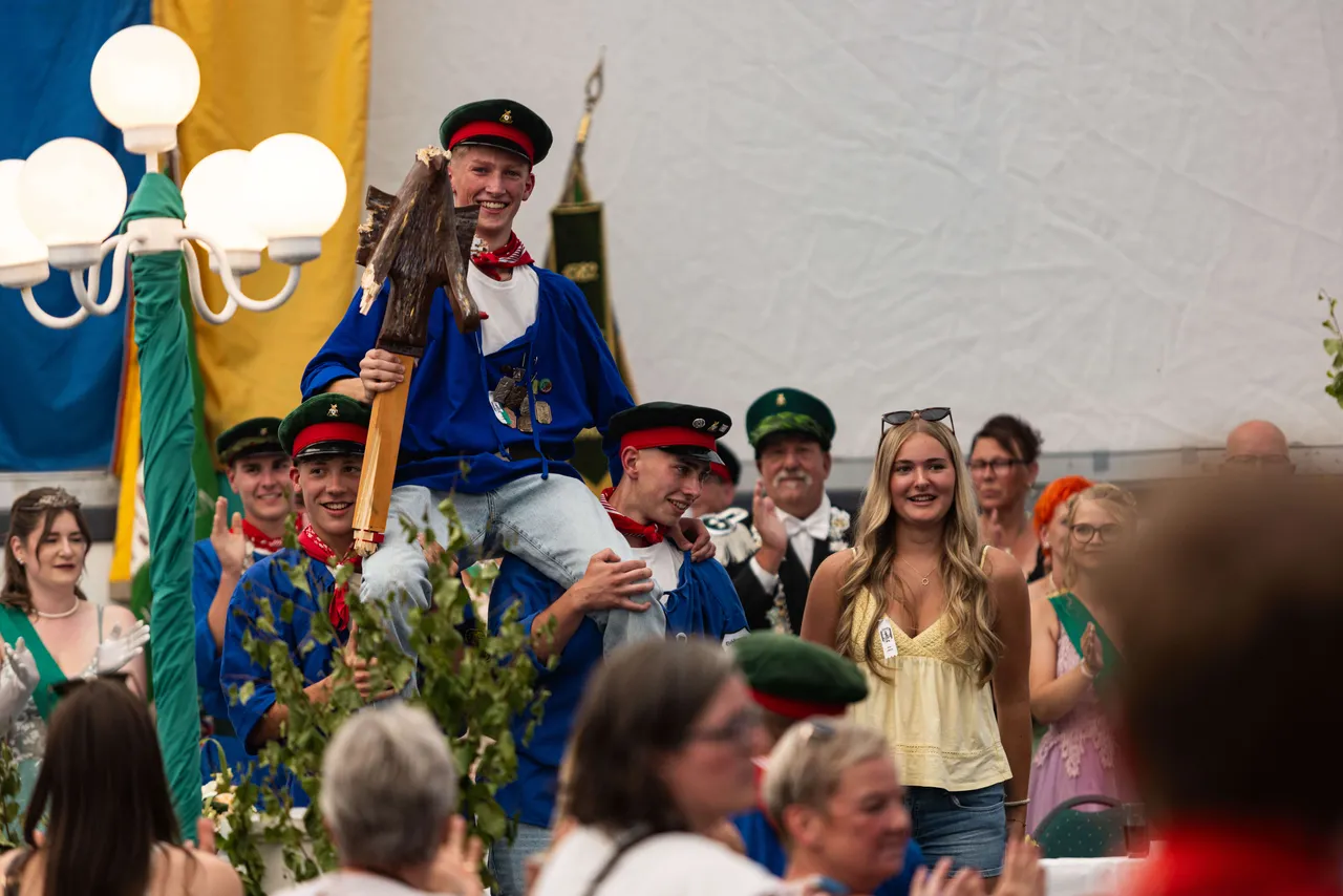 Luca Benninghaus wird nach dem Schützenfest-Schießen von seinen Kameraden auf den Schultern getragen, während er den Prinzenstab hält.
