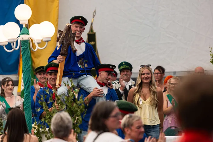 Luca Benninghaus wird nach dem Schützenfest-Schießen von seinen Kameraden auf den Schultern getragen, während er den Prinzenstab hält.