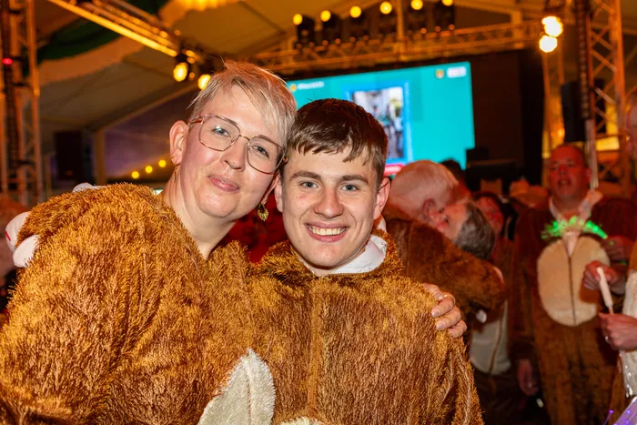 Eine Frau mit Brille und ein junger Mann in braunen, pelzigen Kostümen lächeln bei einem Schützenfest.