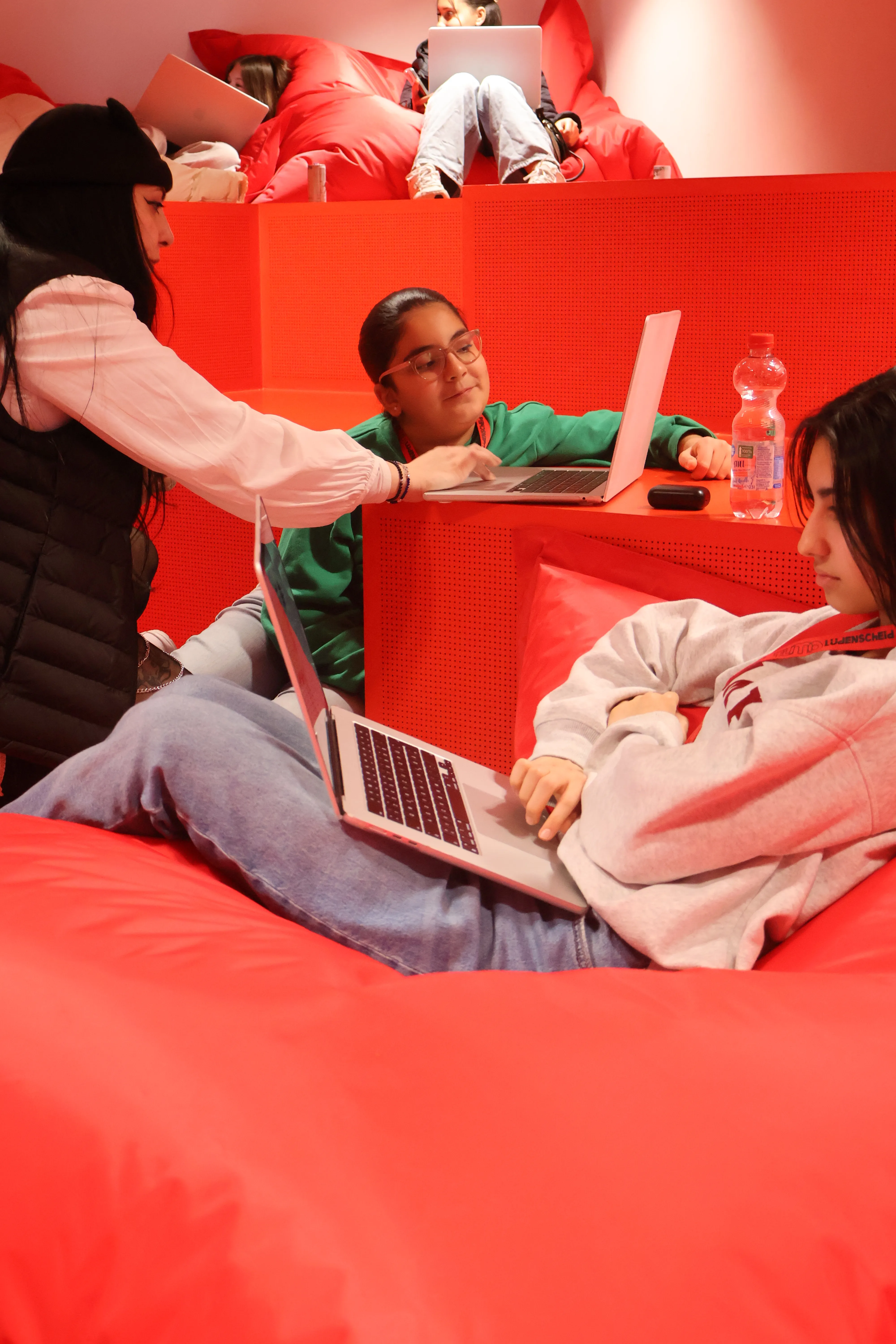 Drei junge Frauen arbeiten mit Laptops in einem rot gestalteten Raum des Tumo Zentrums Lüdenscheid.