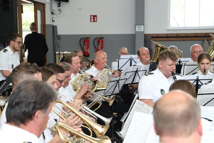 Blasorchester spielt während des Schützenfestes im Landemert. Die Musiker in weißen Uniformen spielen verschiedene Blechblasinstrumente.