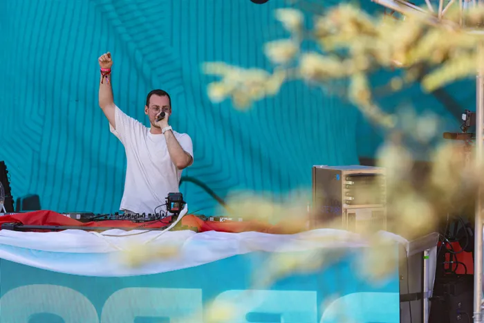 Ein Mann in einem weißen T-Shirt hebt die Faust und hält ein Mikrofon während eines Auftritts beim Ferik Festival.