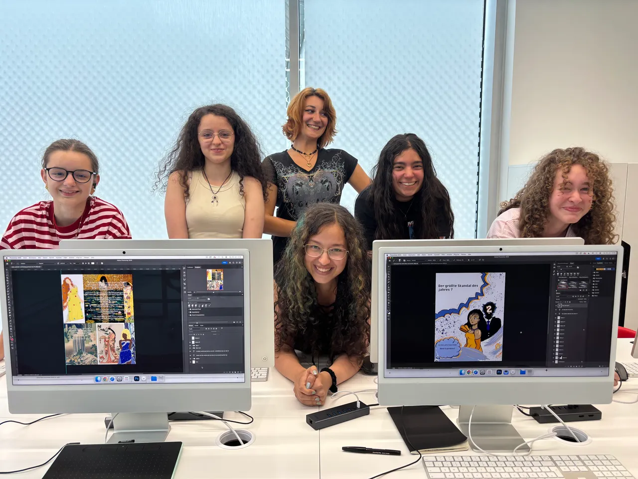 Sechs Jugendliche sitzen in einem Designstudio vor Computermonitoren, auf denen Magazin-Layouts zu sehen sind.