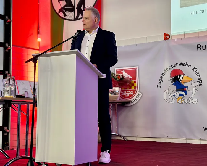 Bürgermeister Olaf Stelse spricht bei einem Stadtwehrappell ans Publikum, ein Podest mit Blumen und Getränken steht neben ihm.