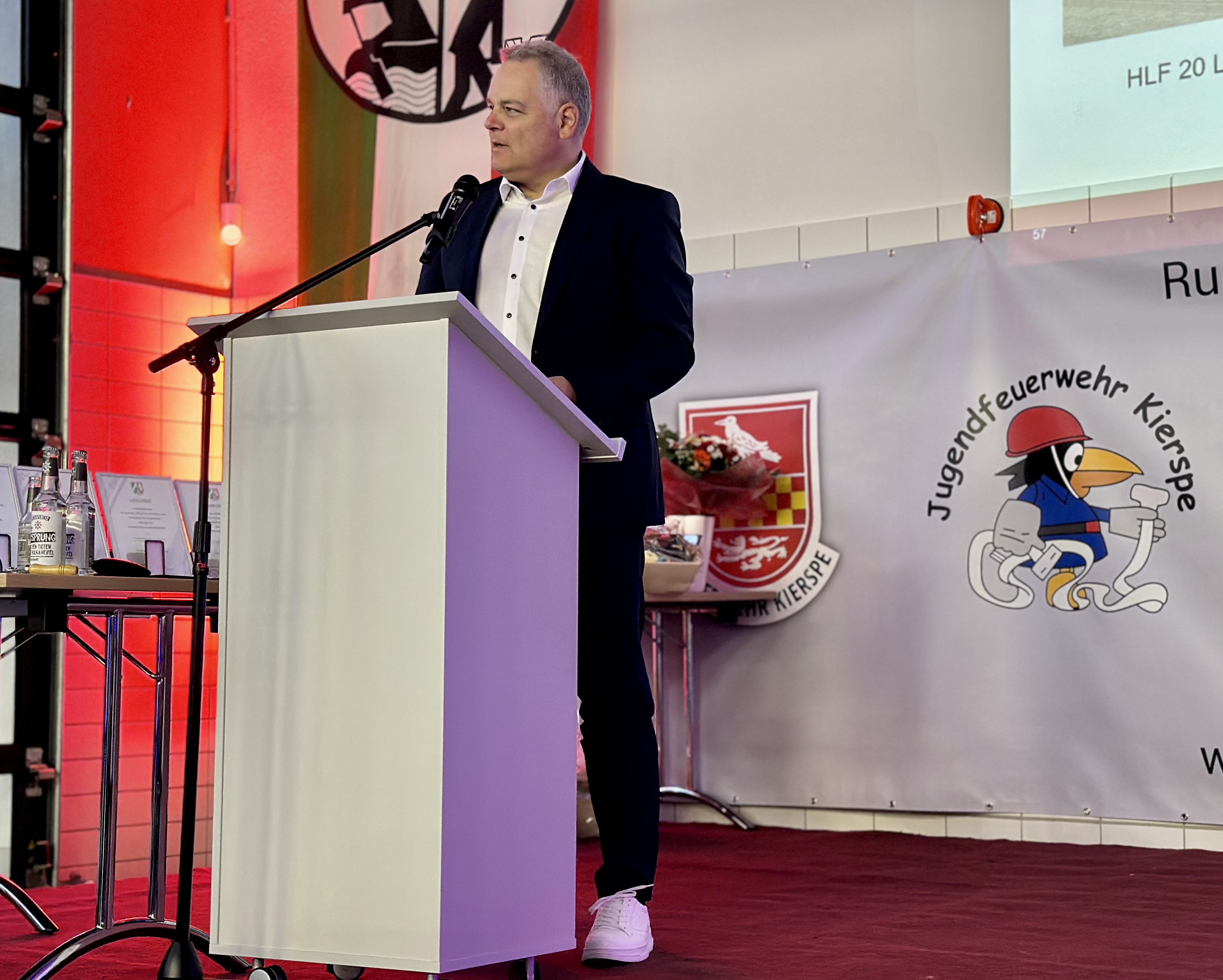 Bürgermeister Olaf Stelse spricht bei einem Stadtwehrappell ans Publikum, ein Podest mit Blumen und Getränken steht neben ihm.