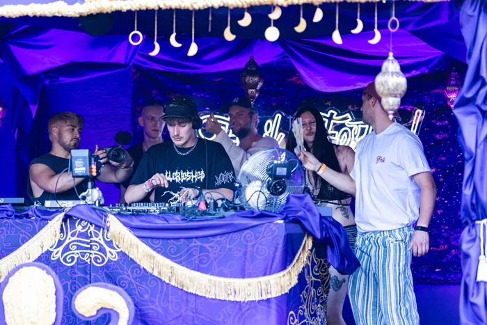 DJs an einem Mischpult vor einer lila-goldenen Kulisse mit Mond-Dekoration beim Ferik Festival.