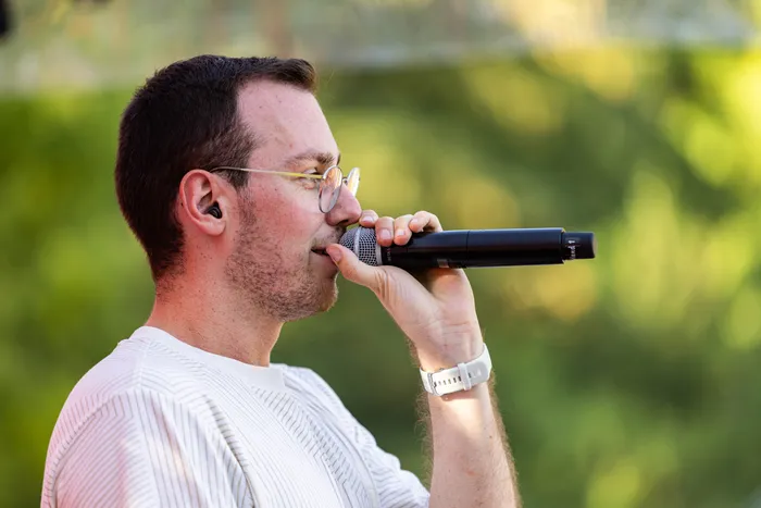 Ein Mann mit Brille und In-Ear-Monitor hält ein Mikrofon an den Mund beim Ferik Festival.