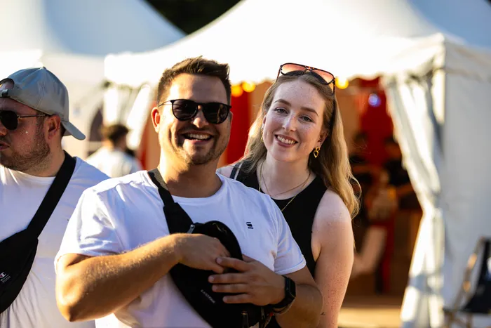 Ein lächelnder Mann und eine Frau stehen vor weißen Zelten beim Ferik Festival.