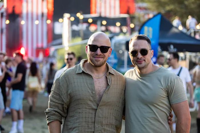 Zwei lächelnde Männer mit Sonnenbrillen stehen eng beieinander auf dem Ferik Festival.