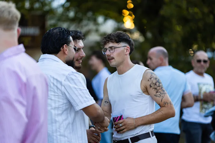 Ein junger Mann mit Brille und Tattoos unterhält sich mit einem anderen Mann beim Ferik Festival.
