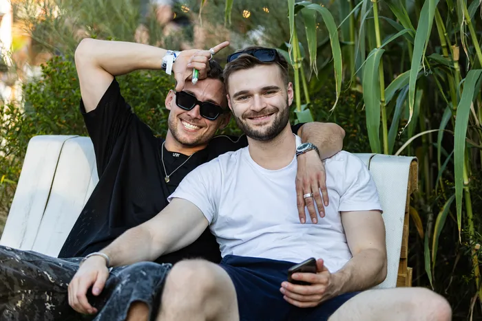 Zwei lächelnde Männer sitzen auf einem weißen Sofa im Freien beim Ferik Festival.