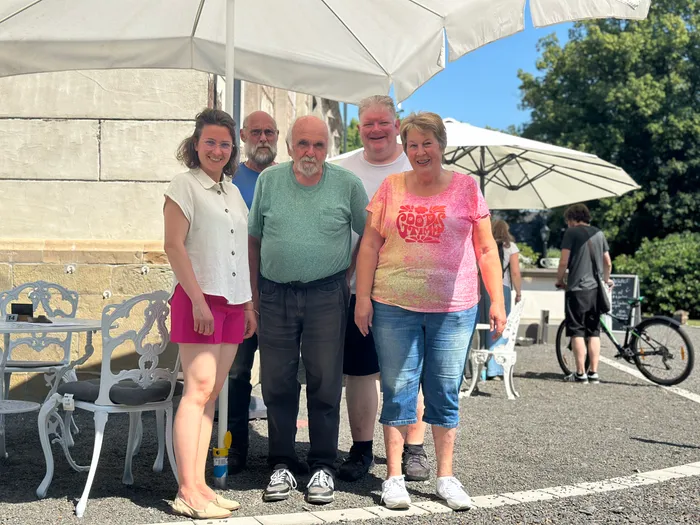 Bella Hettich, Ulrich Finke, Karl-Friedrich Marcus, Holger Scheel und Regina Marcus, die Dorfpaten von Rönsahl, stehen lächelnd vor Sonnenschirmen und Tischen. Im Hintergrund sind weitere Besucher und ein Fahrrad zu sehen.
