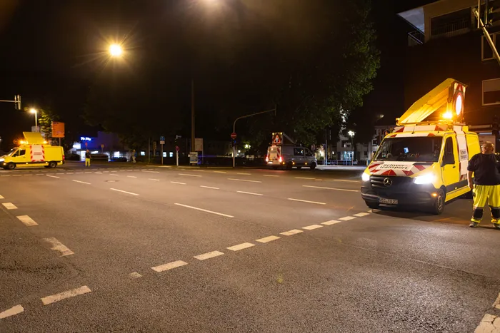 Zwei gelbe Schwertransportfahrzeuge mit eingeschalteten Warnleuchten stehen nachts an einer Straßenkreuzung.