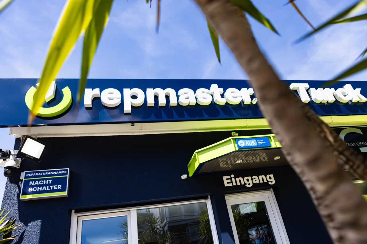 Fassadenansicht der „repmaster“-Werkstatt mit dem Eingangsbereich und Hinweisschildern für Reparaturannahme und Nachtschalter. Das Logo von „repmaster“ und „Turck“ sind gut sichtbar.