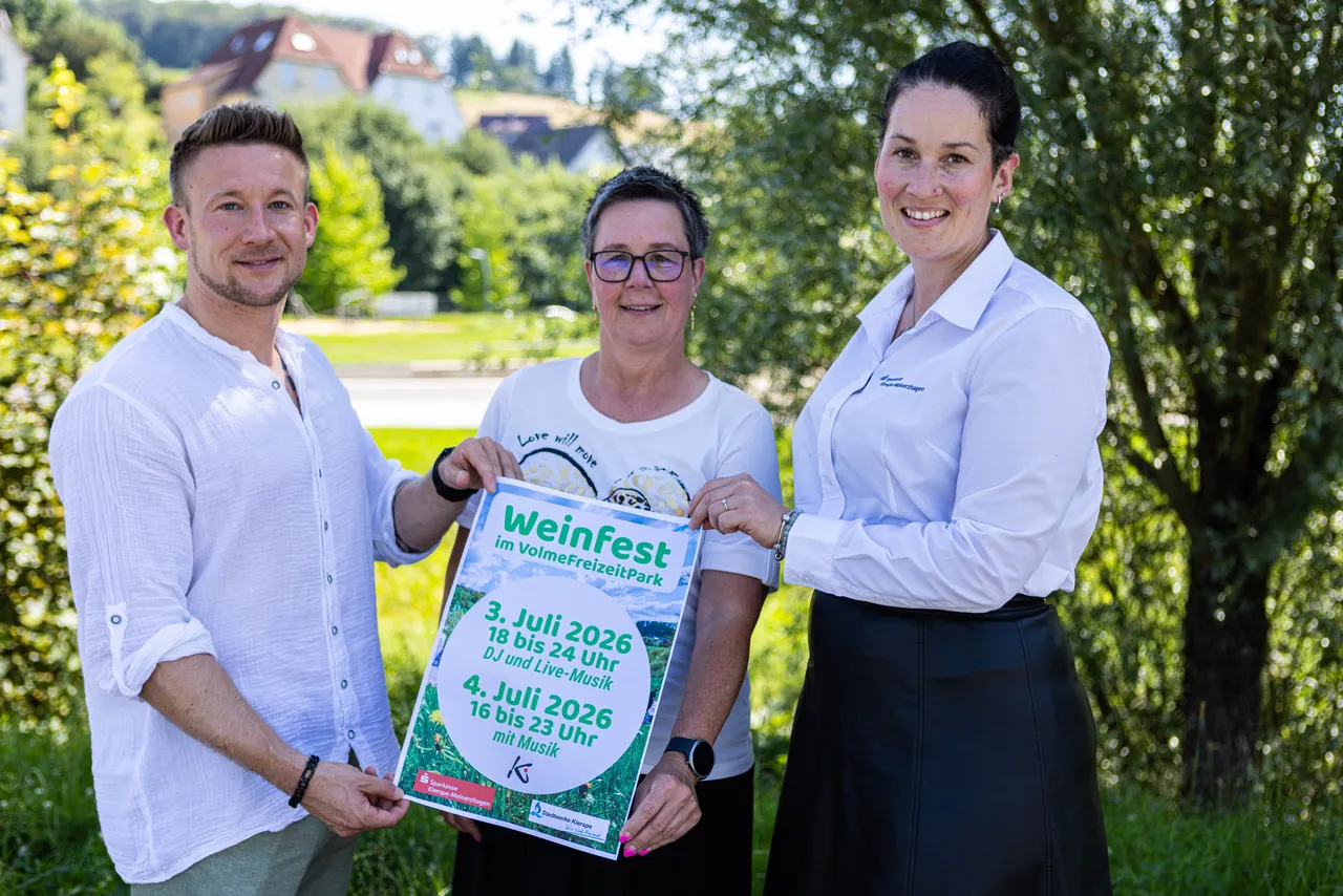 Drei Personen halten ein Werbeplakat für das Weinfest im VolmeFreizeitpark vom 3. und 4. Juli 2026. Von links: Phillip Plachta (Stadtwerke), Regina Semeraro (Stadt Kierspe) und Sina Berges (Sparkasse).