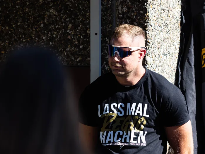 Ein Mann mit Sonnenbrille und einem schwarzen T-Shirt mit der Aufschrift „LASS MAL REGIO MACHEN“ blickt zur Seite.
