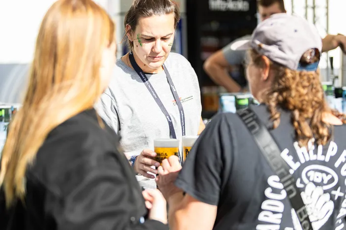 Eine Mitarbeiterin in einem grauen T-Shirt reicht Kunden beim Bautz-Festival Biergläser.