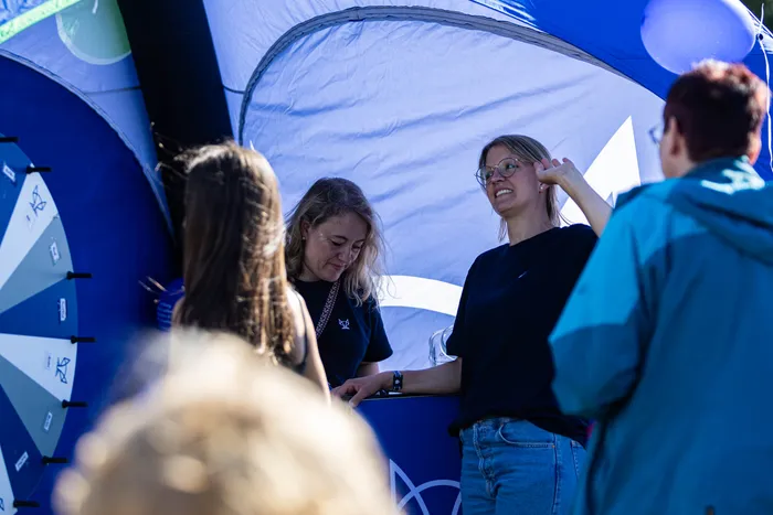 Menschen stehen an einem blauen aufblasbaren Stand beim Bautz-Festival bei Sonnenschein.