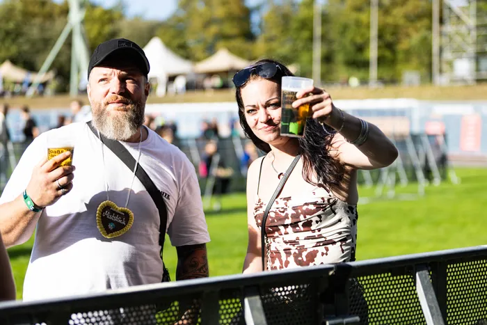 Ein bärtiger Mann mit schwarzer Kappe und eine Frau halten Gläser mit Bier auf dem Bautz-Festival in die Höhe.