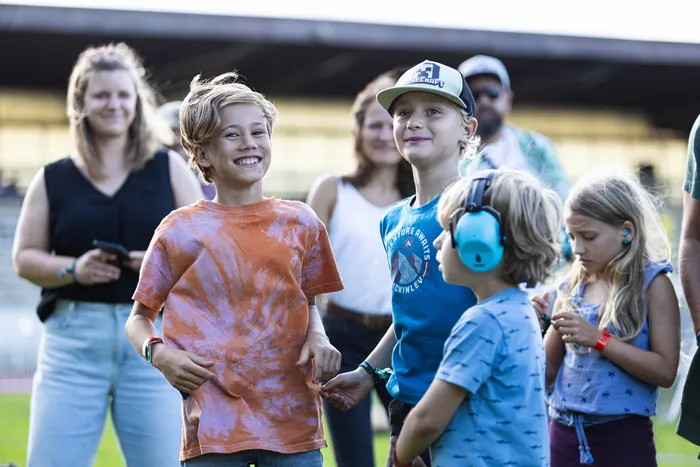 Ein lächelnder Junge in einem orangefarbenen Tie-Dye-Shirt und ein Junge mit Minecraft-Kappe und blauem Gehörschutz auf dem Bautz-Festival.
