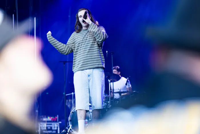 Baumgart singt mit erhobenem Arm in ein Mikrofon auf der MainStage des Bautz-Festivals unter blauem Licht.