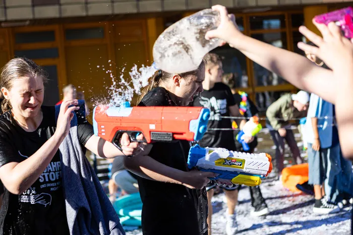 People playfully spray each other with water guns during a summer water fight at the Rothenstein School in Meinerzhagen.