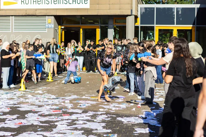 Schüler feiern ausgelassen mit Wasserpistolen und Konfetti vor der Rothensteinschule in Meinerzhagen.