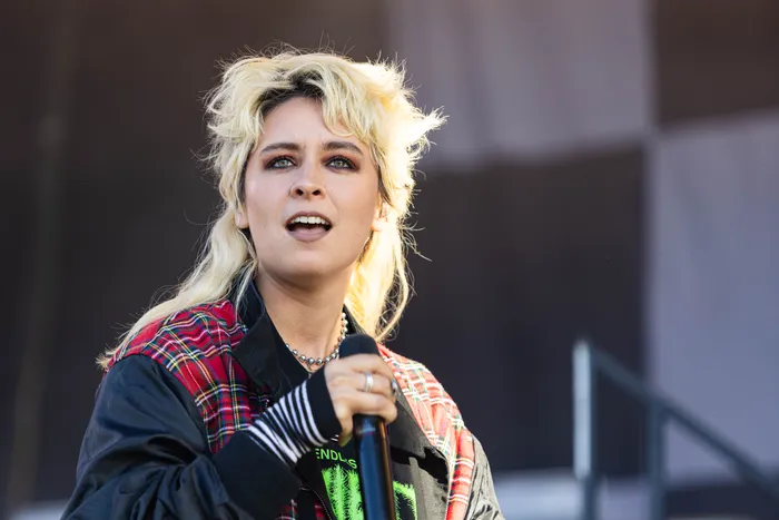 Paula Carolina mit voluminösem blondem Haar und einer rot karierten Jacke singt in ein Mikrofon beim Bautz-Festival 2026.