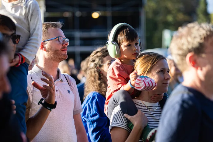 Zuschauer beim Bautz-Festival, ein Kind mit grünen Kopfhörern sitzt auf den Schultern einer Frau.