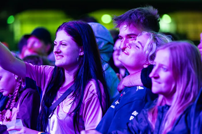 Menschen im Publikum bei einem Konzert der Band Juli, beleuchtet von violettem Licht.
