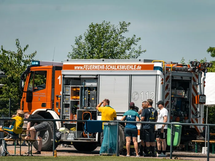 Feuerwehrauto der Feuerwehr Schalksmühle mit der Aufschrift www.feuerwehr-schalksmuehle.de, umgeben von Zuschauern bei einem Sommercup.