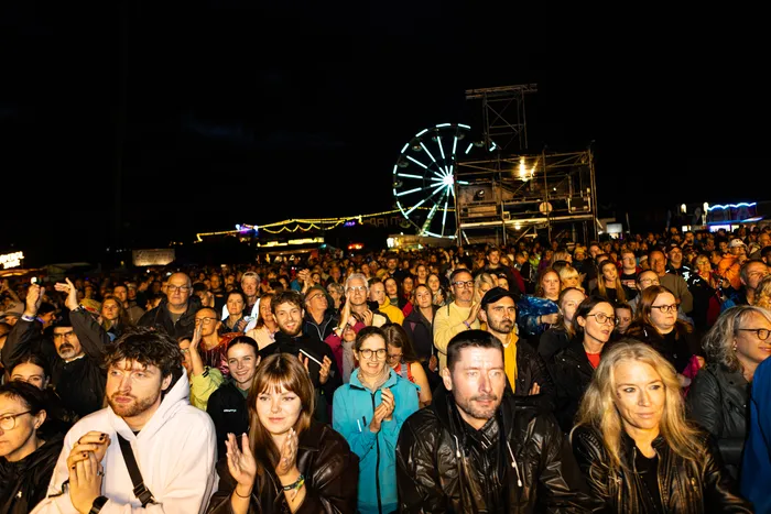 Eine große Menschenmenge bei Nacht vor einem beleuchteten Riesenrad während des Bautz Festivals.