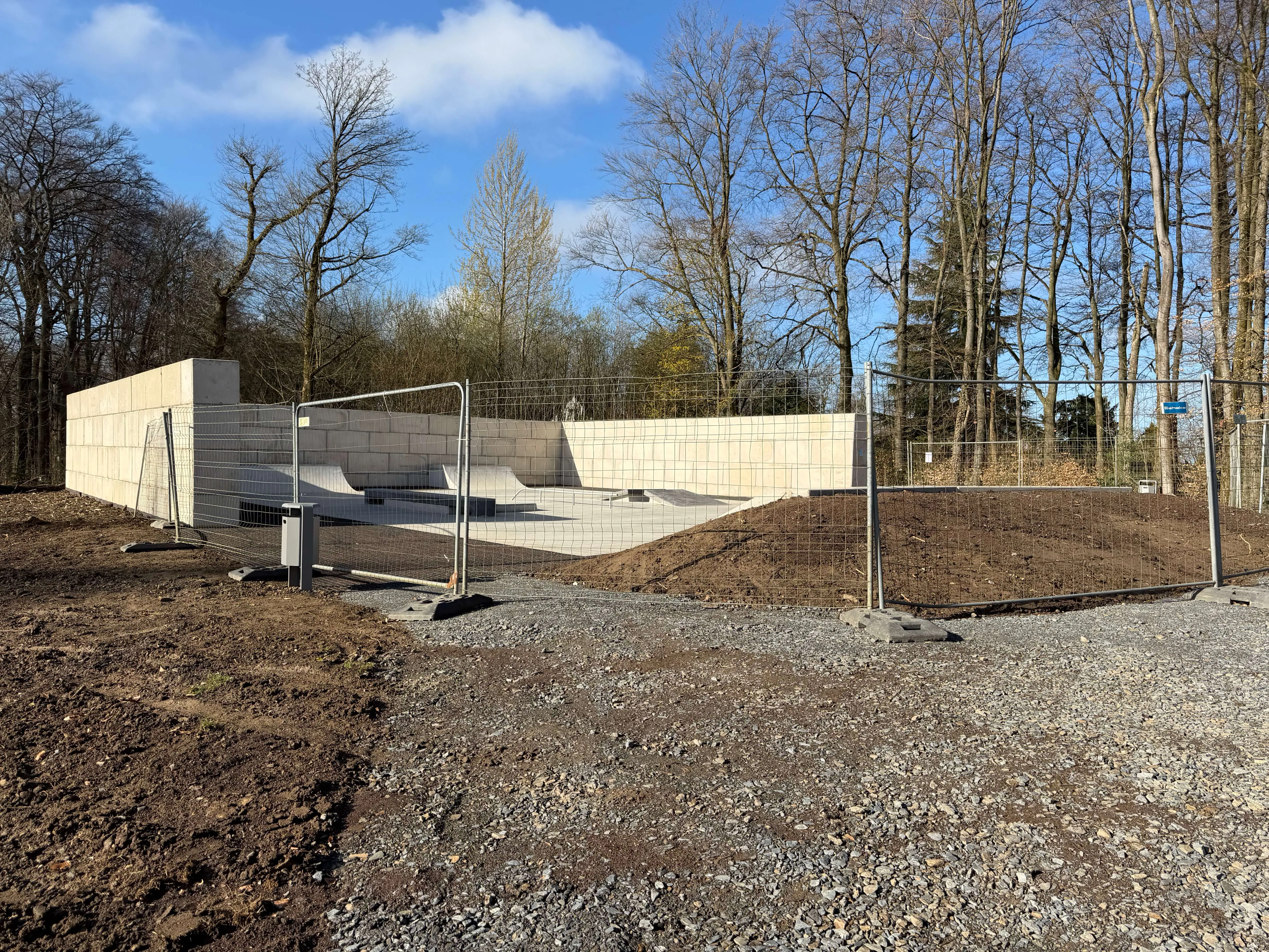Neue Skate- und Bikeanlage in Halver mit Betonrampen und Metallgeländern, umgeben von Bäumen und Bauzäunen.