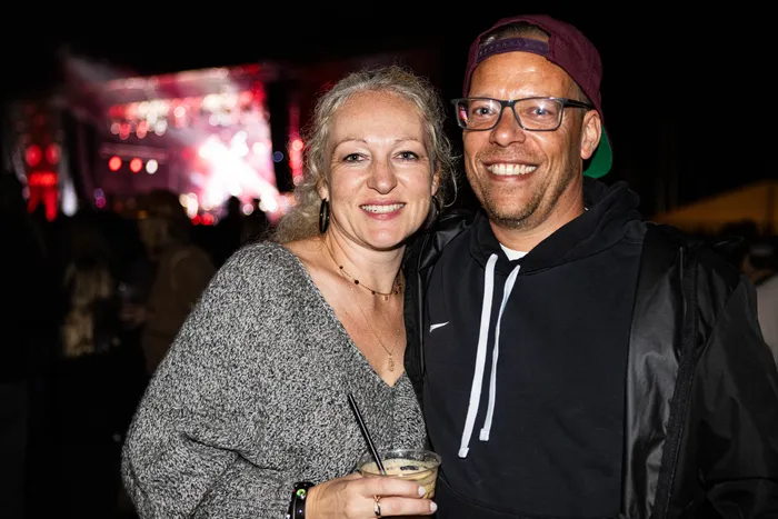 Ein lächelndes Paar steht vor einer hell erleuchteten Bühne beim Bautz-Festival 2026. Die Frau hält ein Getränk in der Hand.