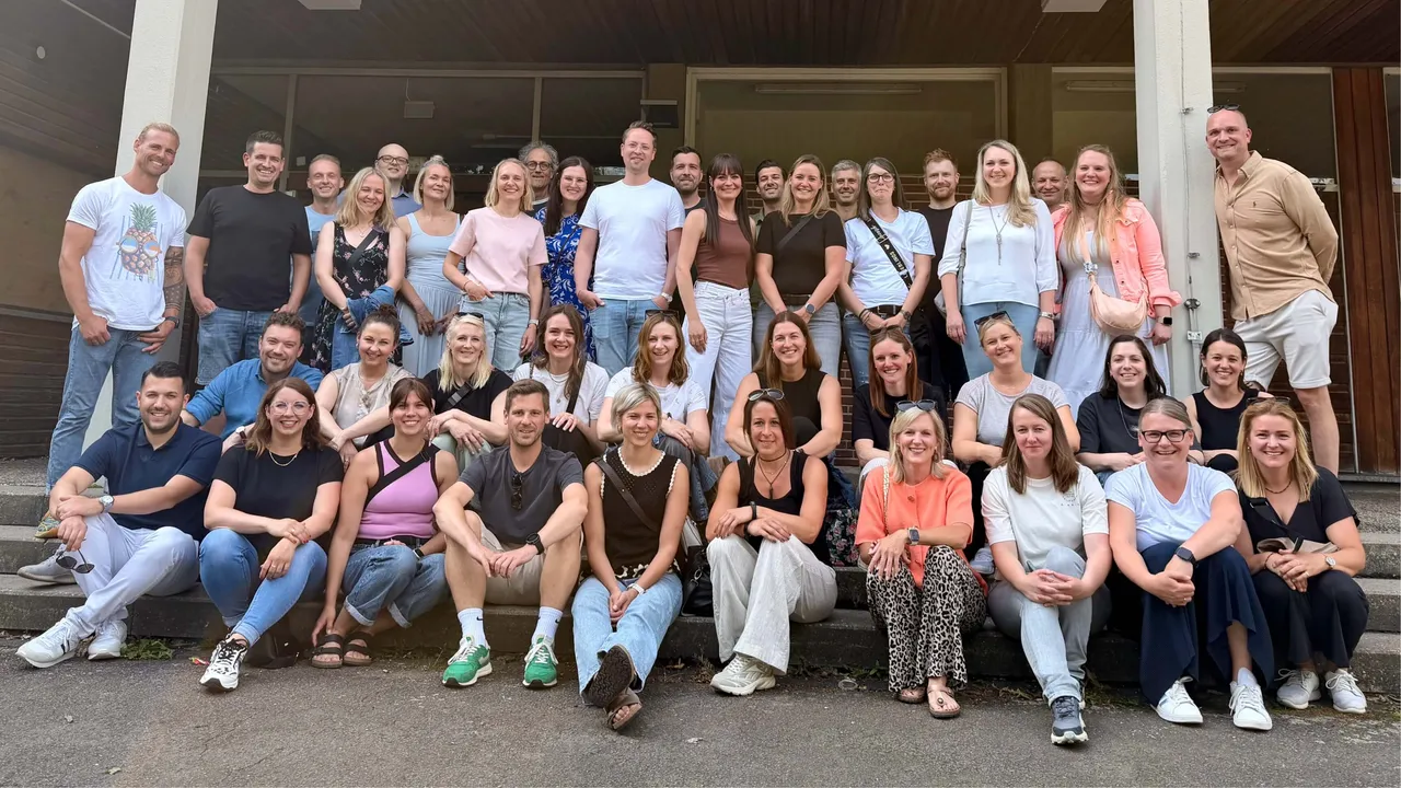 Gruppe von etwa 40 ehemaligen Schülerinnen und Schülern des Evangelischen Gymnasiums Meinerzhagen posiert auf der Treppe vor dem Schulgebäude.