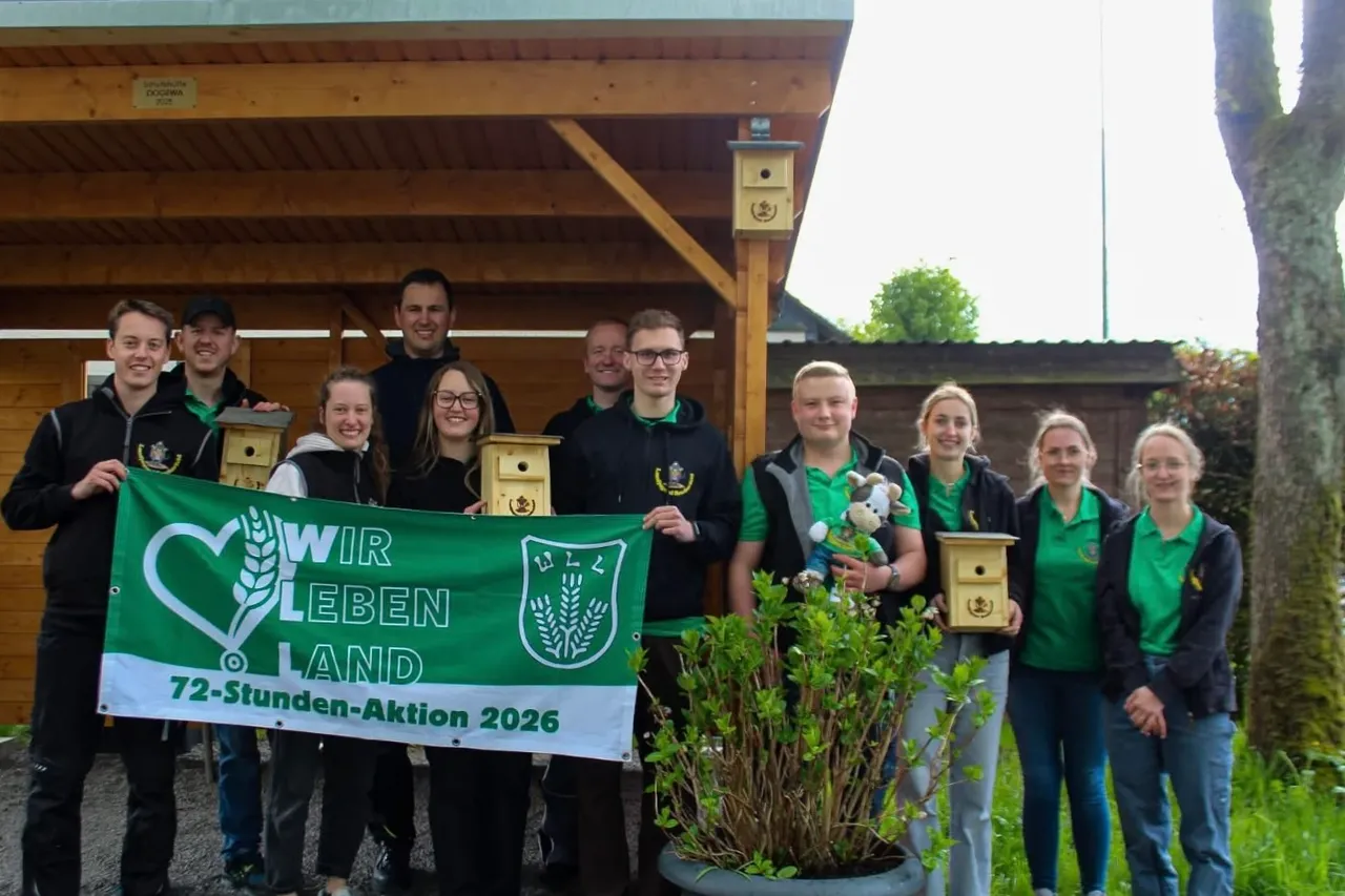 Eine Gruppe junger Menschen hält ein grünes Banner mit der Aufschrift „Wir leben Land“ und präsentiert selbstgebaute Nistkästen.