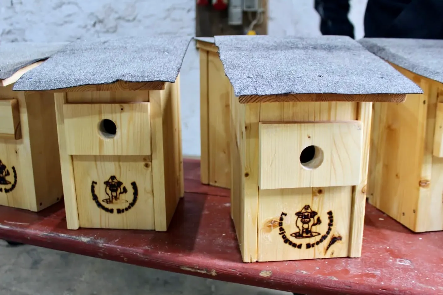 Vogelhäuser aus Holz mit Schindeldach und dem Logo der Breckerfelder Landjugend.